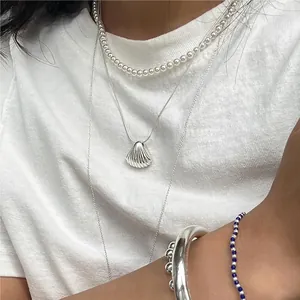 Close-up of layered 925 silver necklaces with shell pendant and pearl strand set