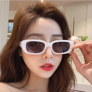 Close-up of stylish white rectangular sunglasses with dark gradient lenses on a model