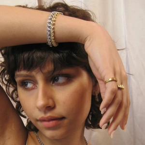 Detail shot of model wearing a stacked stainless steel jewelry set with zircon bracelets