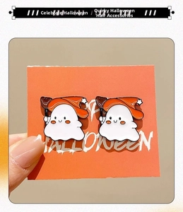 Detail of Halloween ghost earrings with orange wizard hats on a festive gift card