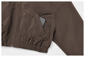Detailed view of deep brown windbreaker jacket with elastic hem and functional side pocket