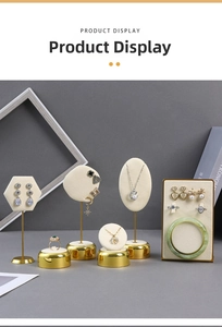 Detail view of cream velvet jewelry display set with gold metal bases on dark background
