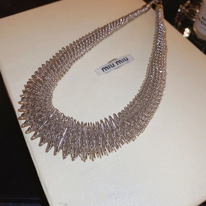 Close-up of a chunky silver spring-coil choker necklace with industrial texture