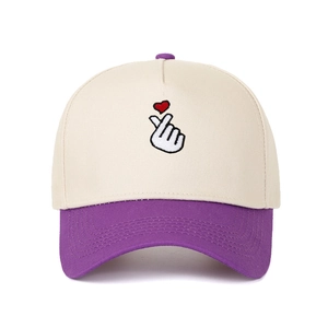 Detailed embroidery of a red finger heart on a beige and purple five-panel baseball cap