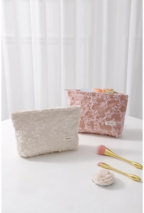 Close-up of corduroy makeup bag with 3D floral lace embroidery and H&R BAG logo label