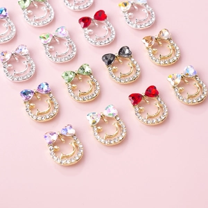 Close-up of horseshoe-shaped nail art charms with crystal bow accents in various colors
