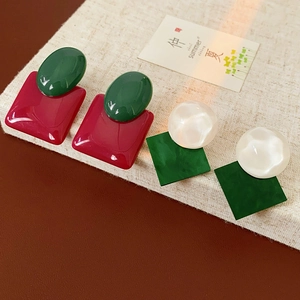 Macro shot of retro geometric resin earrings in contrasting red, green, and white colors