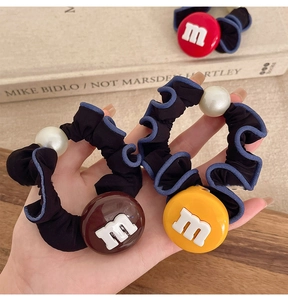 Détail de chouchous en tissu avec breloques de bonbons lettre M et grandes perles