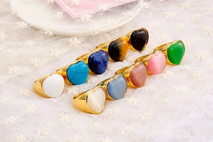 Collection of gold heart rings with colorful gemstones on a white lace fabric background