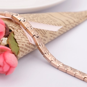 Roségoldenes Edelstahl-Gliederarmband mit Germanium-Steinen auf einer Papierrolle