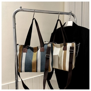 Detail view of striped canvas tote bags in blue and yellow hanging on a metal rack