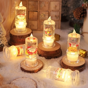 Close-up of LED glowing Christmas candle with Santa figure and glitter inside snowy decor