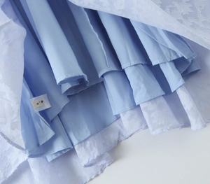 Detail shot of light blue layered dress with white tulle overlay and size S label