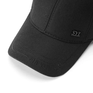 Detail of black cotton baseball cap showing metal logo plaque and embroidery work