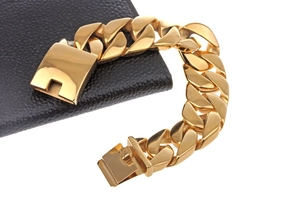 Macro shot of 18k gold plated stainless steel Cuban bracelet with open clasp on leather