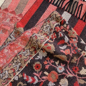 Close-up of woven floral paisley pattern and fringe detail on warm thick winter scarf