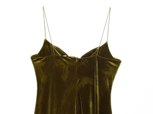 Detail view of olive green velvet dress showing thin straps and back zipper on white background