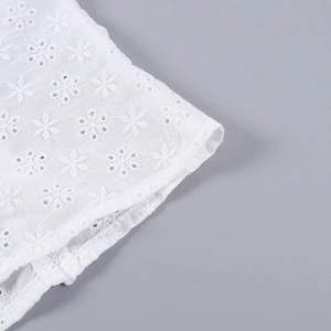 Gros plan sur la broderie florale blanche du haut camisole en dentelle jacquard