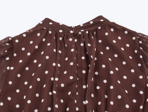 Dettaglio top in chiffon marrone a pois con collo alto e cerniera posteriore invisibile