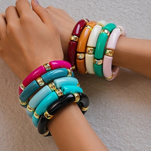 Dettaglio di bracciali colorati in acrilico con distanziali dorati sul polso di una modella