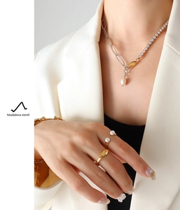 Close-up of minimalist stainless steel chain necklace with white pearl pendant and rings