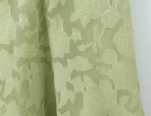 Detailaufnahme von hellgrünem Stoff mit elegantem 3D-Blumenmuster und transparenter Textur