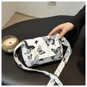 Detail of white canvas crossbody bag featuring large black butterfly pattern and wide strap
