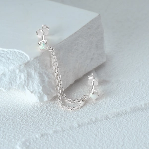 Macro detail of S925 sterling silver chain earrings with shimmering white opals for double piercings