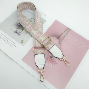 Detail of ethnic geometric jacquard purse strap with gold hardware and pink weaving