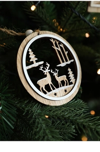 Detail of wooden Christmas ornament with reindeer and stars hanging on a festive tree branch