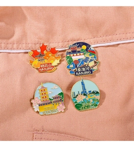 Detail of four colorful Nanjing landmark enamel pins on soft pink fabric background