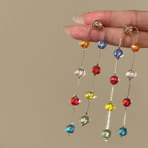 Macro view of long tassel earrings featuring vibrant multicolor faceted glass beads.