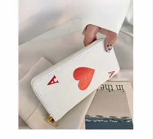 Detail of canvas long wallet with Ace of Hearts design and gold zipper held by hand
