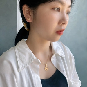 Close-up of golden moon and star jewelry set on a model showing ear studs and necklace