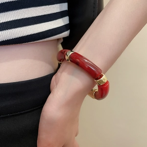 Vue détaillée d'un bracelet en acrylique marbré rouge avec des anneaux dorés polis