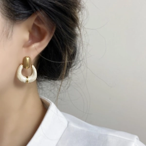 French vintage gold plated U-shaped cream enamel earrings worn by a model