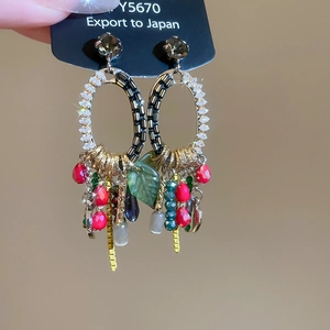 Detailed shot of gold hoop earrings with rhinestones, colorful beads and chain tassels
