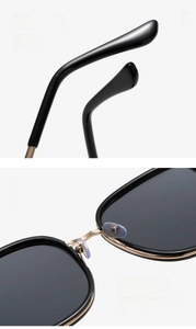 Detailed macro view of black sunglasses with gold metal bridge and integrated nose pads