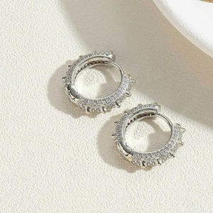 Close-up of silver hoop earrings featuring pavé cubic zirconia and small punk spike details