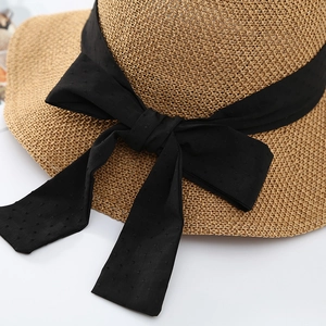 Dettaglio cappello di paglia naturale con ampio fiocco nero e trama a pois in rilievo
