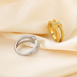 Close-up of 18K gold and silver crisscross knot rings with textured bands and diamonds