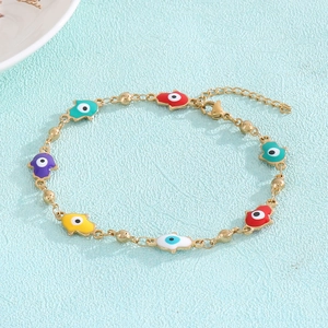 Detail of gold evil eye bracelet with colorful enamel palm charms on blue leather background