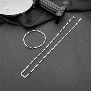 Ensemble collier et bracelet en acier inoxydable poli argenté sur une surface sombre
