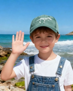 Close-up of a vintage green kids baseball cap featuring white dinosaur skeleton embroidery
