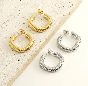 Detailed view of gold and silver textured twist hoop earrings on a stone surface