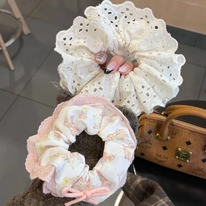 Dettaglio di scrunchie in pizzo ricamato e elastico con stampa di coniglio e fiocco rosa
