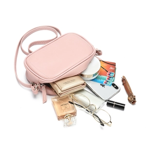 Minimalist light pink PU leather crossbody bag shown with daily essentials on white background