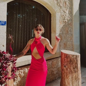 Detail of red halter dress featuring a 3D floral appliqué and gathered body texture