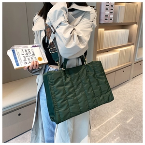 Detail of green quilted nylon tote bag featuring a patterned wide shoulder strap