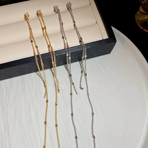 Detailed close-up of gold and silver long tassel earrings with zircon on a jewelry box